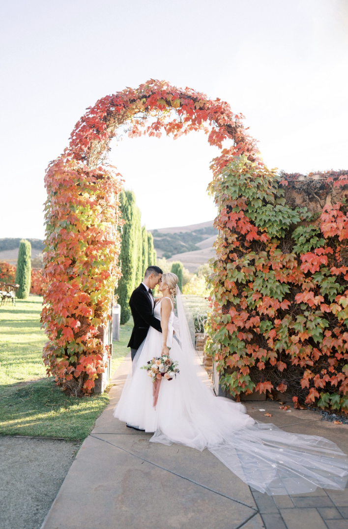 Couple beneath the ivy-covered arch at sunset