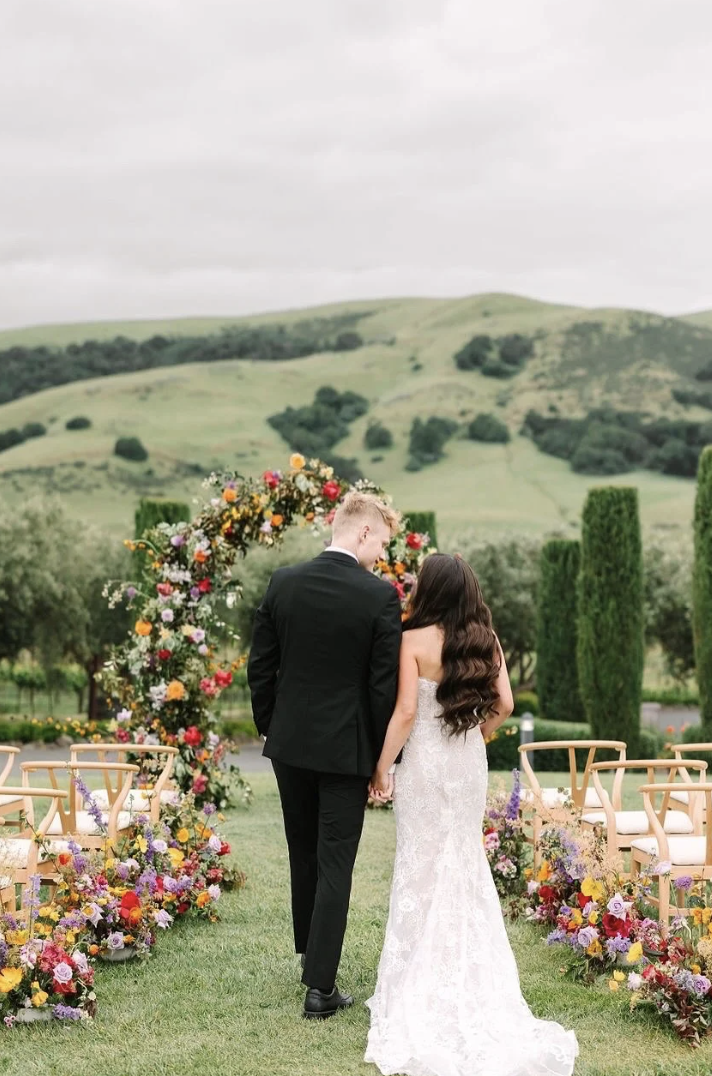 Bride and groom walking down the aisle beneath floral arrangements